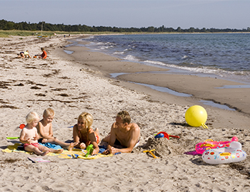 Familie med to børn ligger på stranden i Gedesby